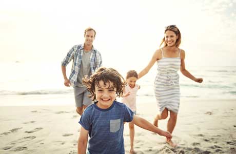 happy parents and children running along beach  